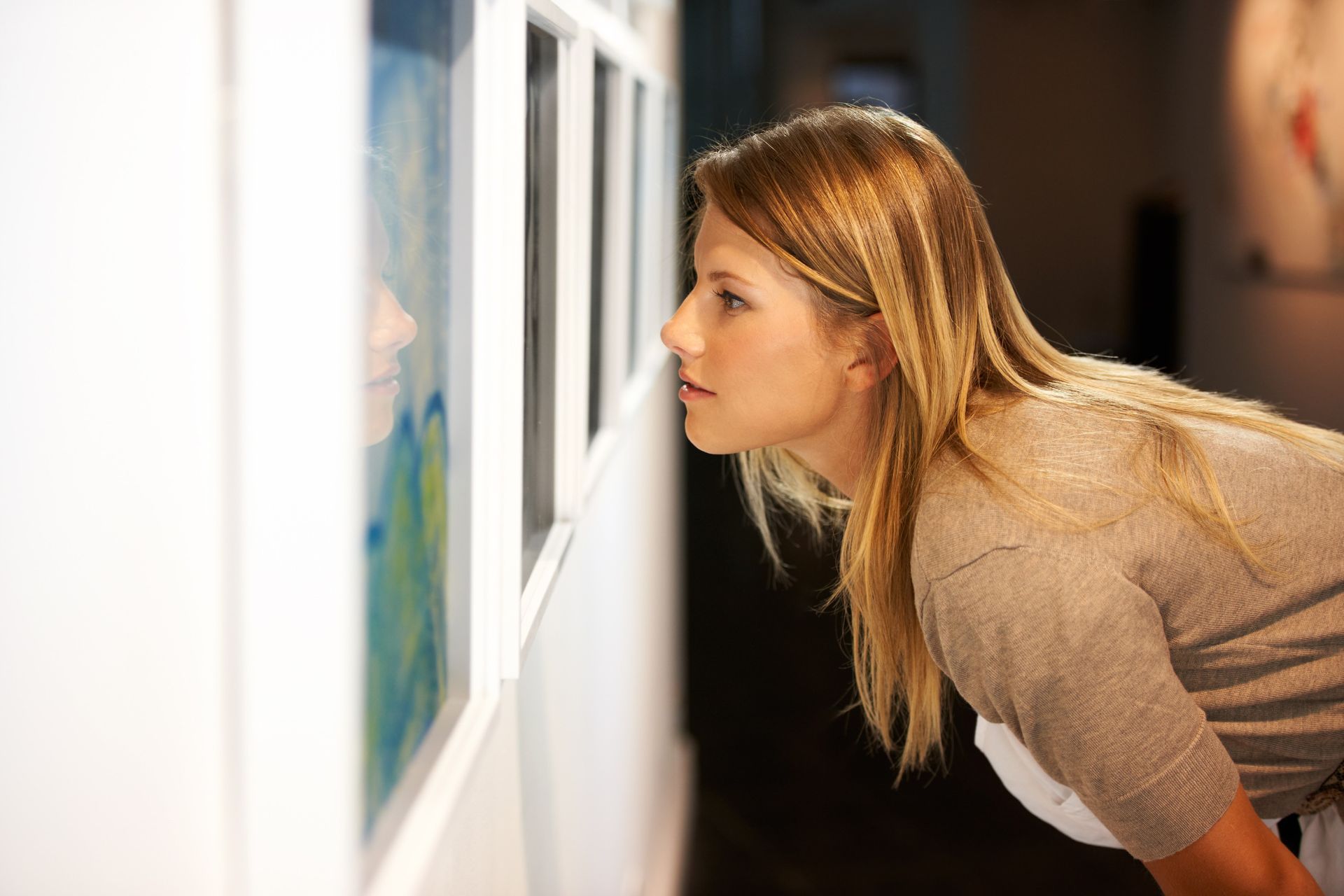 Una mujer está mirando un cuadro en una galería de arte.