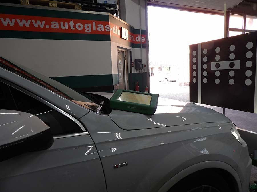 Ein weißes Auto steht in einer Garage von F&B Autoglas GmbH