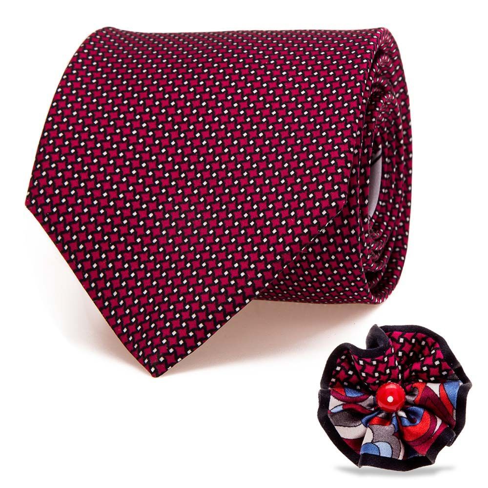 Cravate à motifs bordeaux, roulée, avec broche assortie.