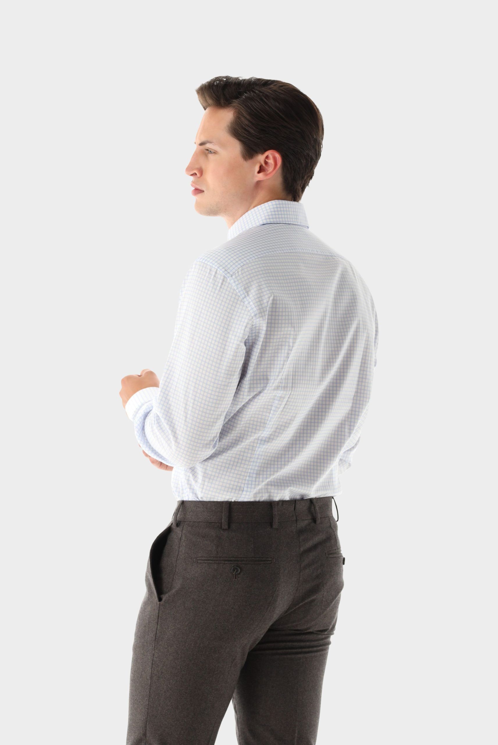 Homme en chemise à rayures bleues et pantalon gris, regardant à gauche.