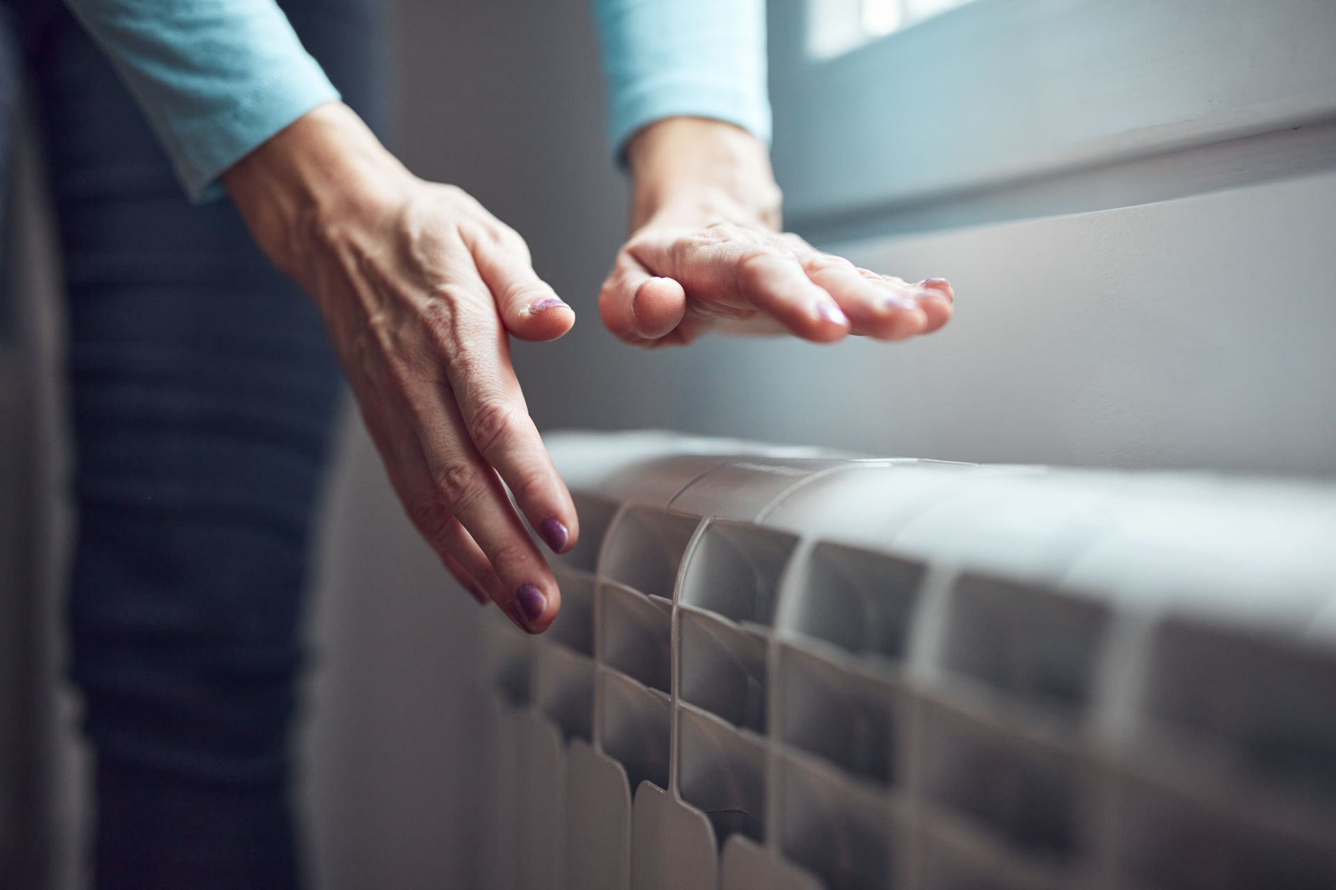 Mains de femme vérifiant la température d'un radiateur
