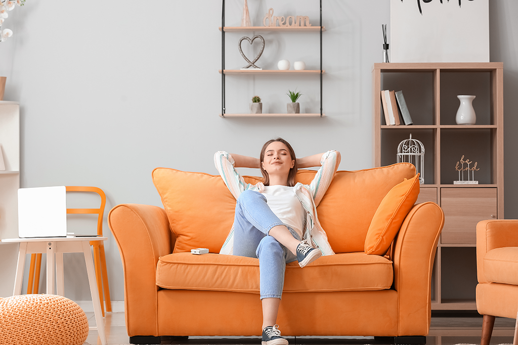 Jeune femme se reposant sur un canapé orange dans le salon