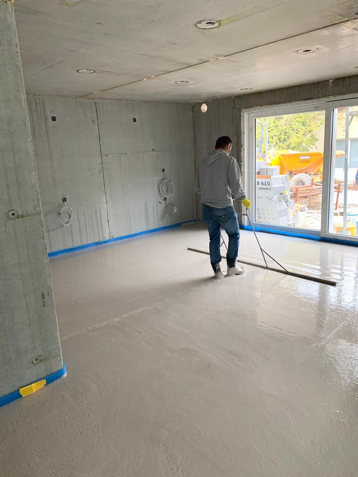 Une pièce en construction avec un sol en béton fraîchement coulé, 
