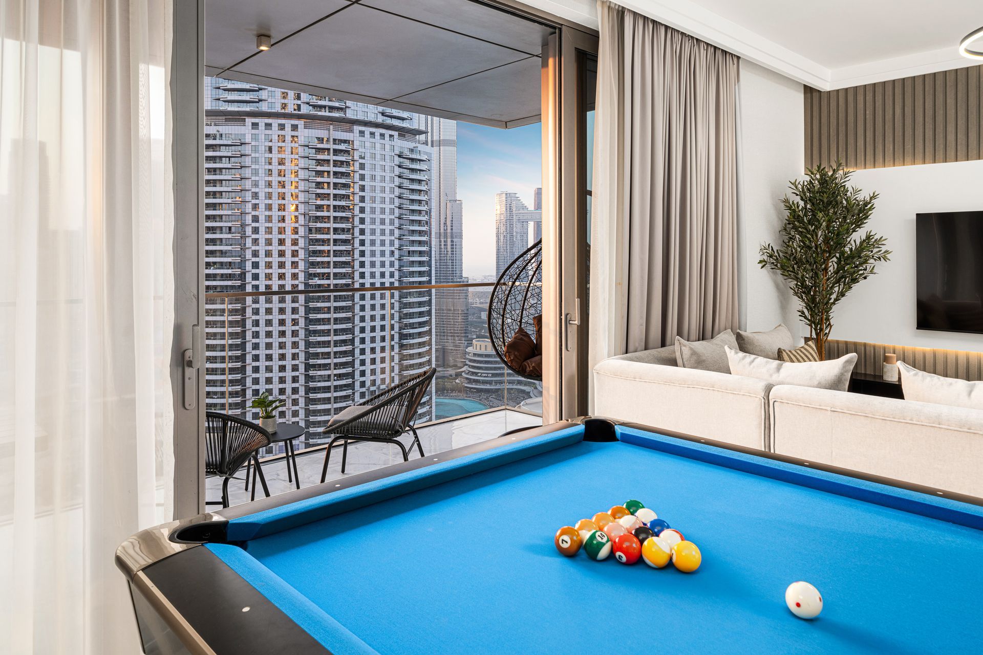 Pool table in a modern living room with Burj Khalifa view from the balcony.