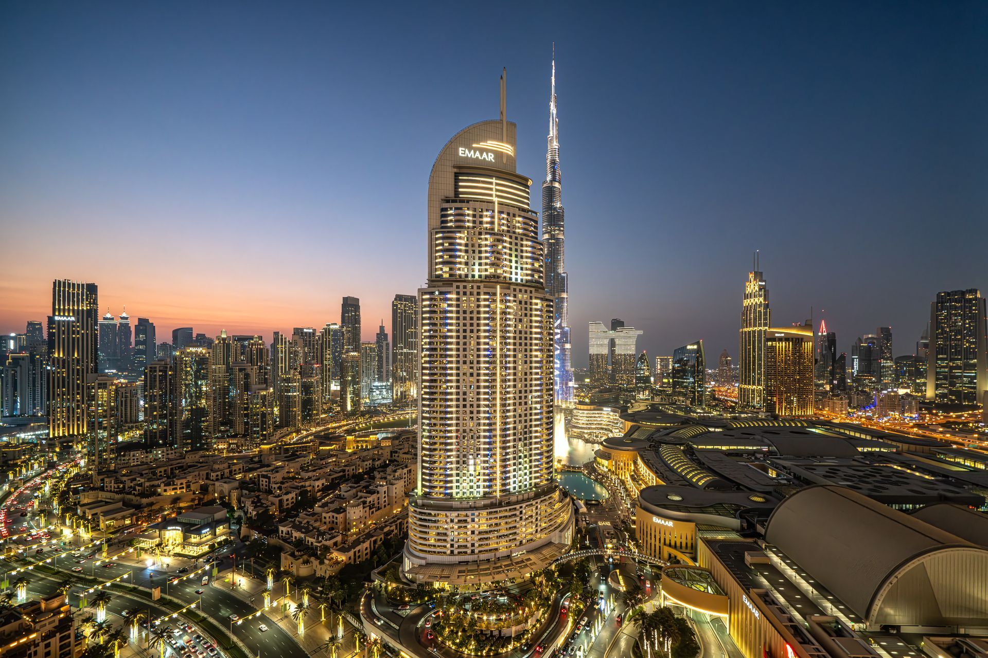 Cityscape at dusk with illuminated skyscrapers, including the Burj Khalifa, Dubai.