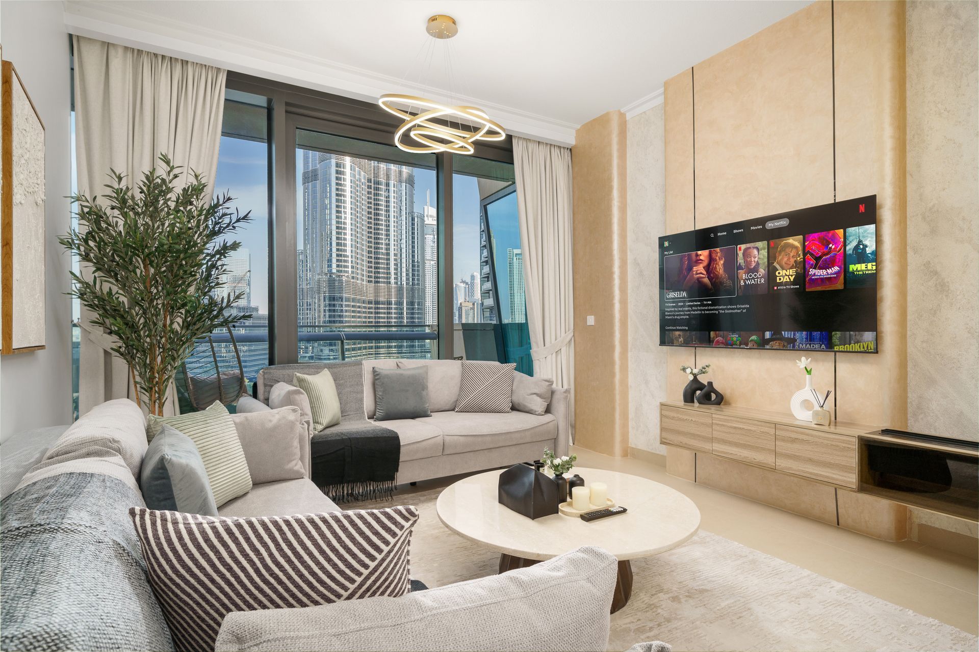 Cozy living room with modern furniture, large windows, and Burj Khalifa view. Beige and gray color scheme.