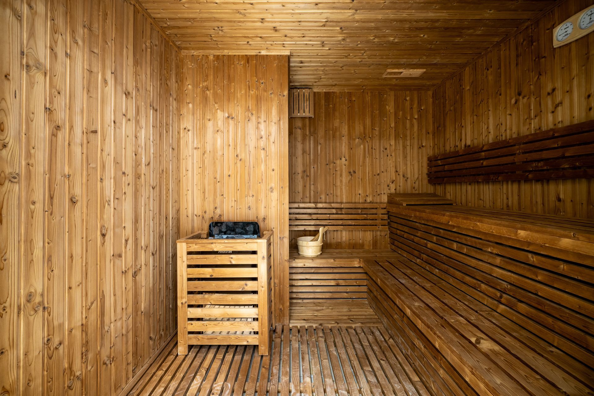 Wooden sauna with benches, heater, and bucket.
