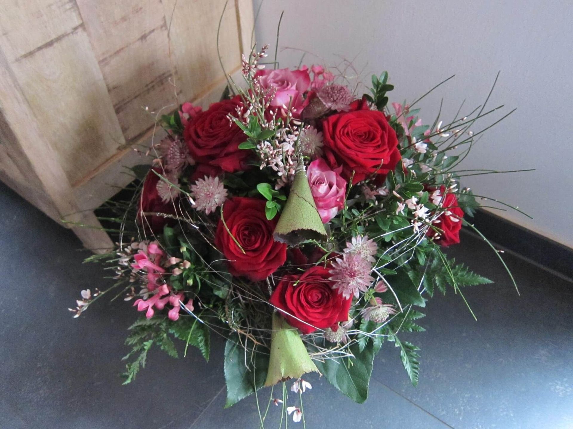 Eleganter Strauß mit roten Rosen, Rosa-Blüten und feinen Grünzweigen.