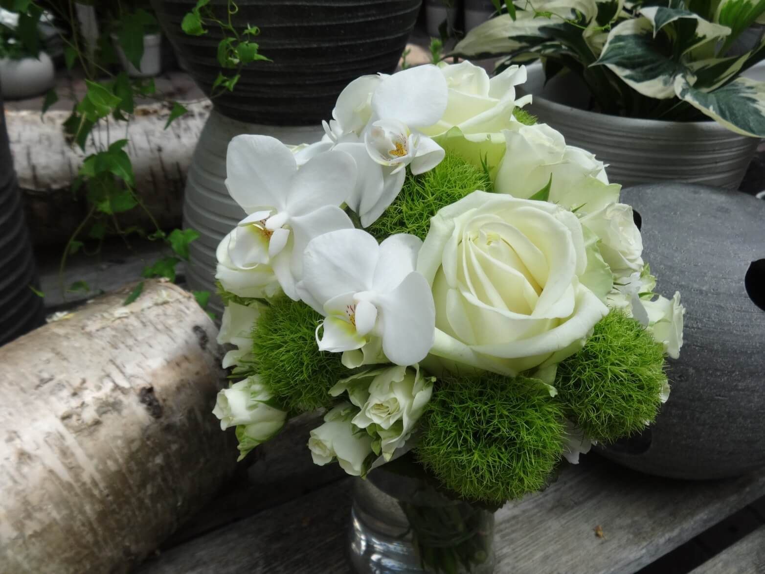 Zarter Brautstrauß in Weiß und Grün mit Rosen, Orchideen und Mooskugeln.