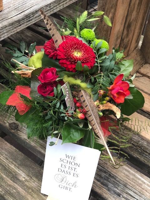 Floristikstrauß in Rot, Grün und Gelb mit Gerbera, Beeren und Naturdekoration.