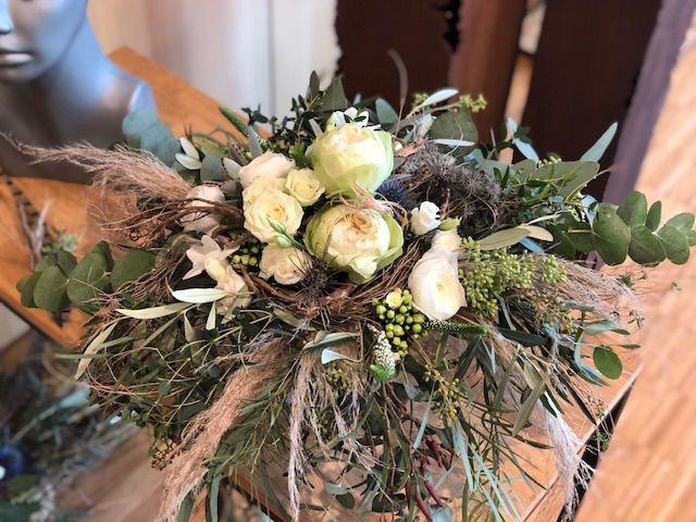 Rustikaler Brautstrauß mit cremefarbenen Rosen, Eukalyptus und getrockneten Naturmaterialien.