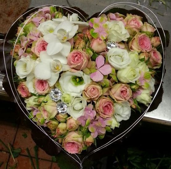 Herzförmiges Trauergesteck mit weißen Orchideen, Rosen und zartem Rosa.