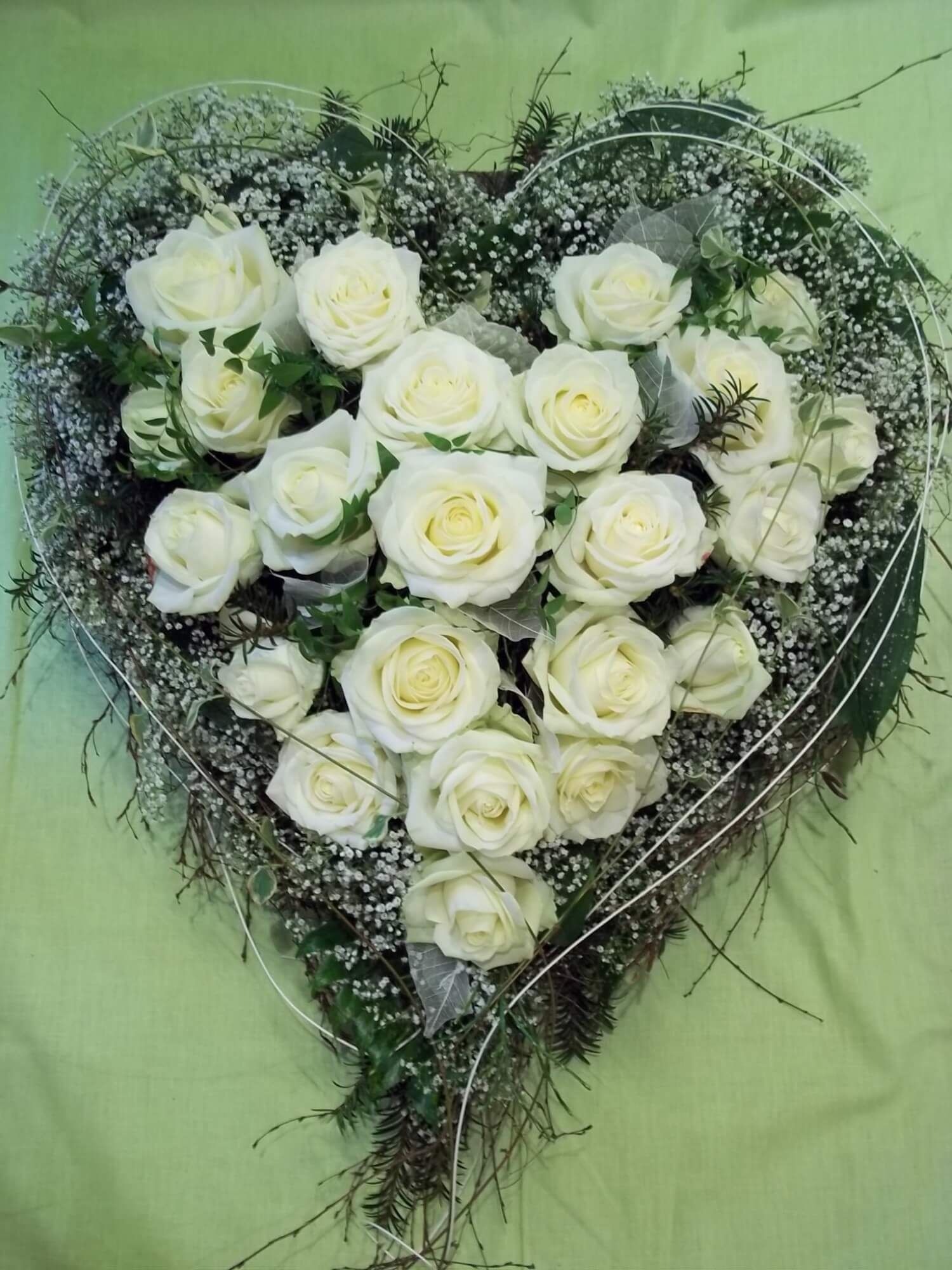 Herzförmiges Trauergesteck mit weißen Rosen und feinem Schleierkraut.