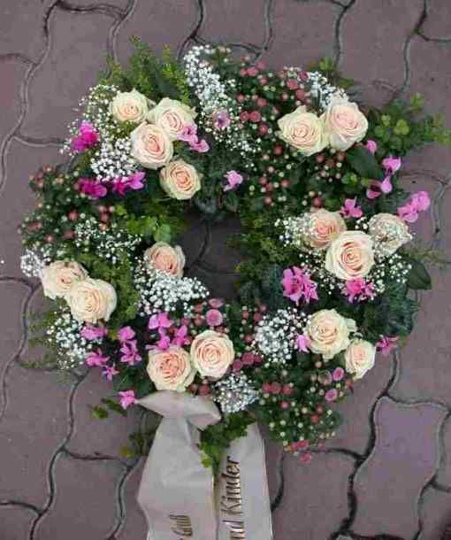 Trauerkranz mit cremefarbenen Rosen, zarten pinken Akzenten und lockerem Grün.