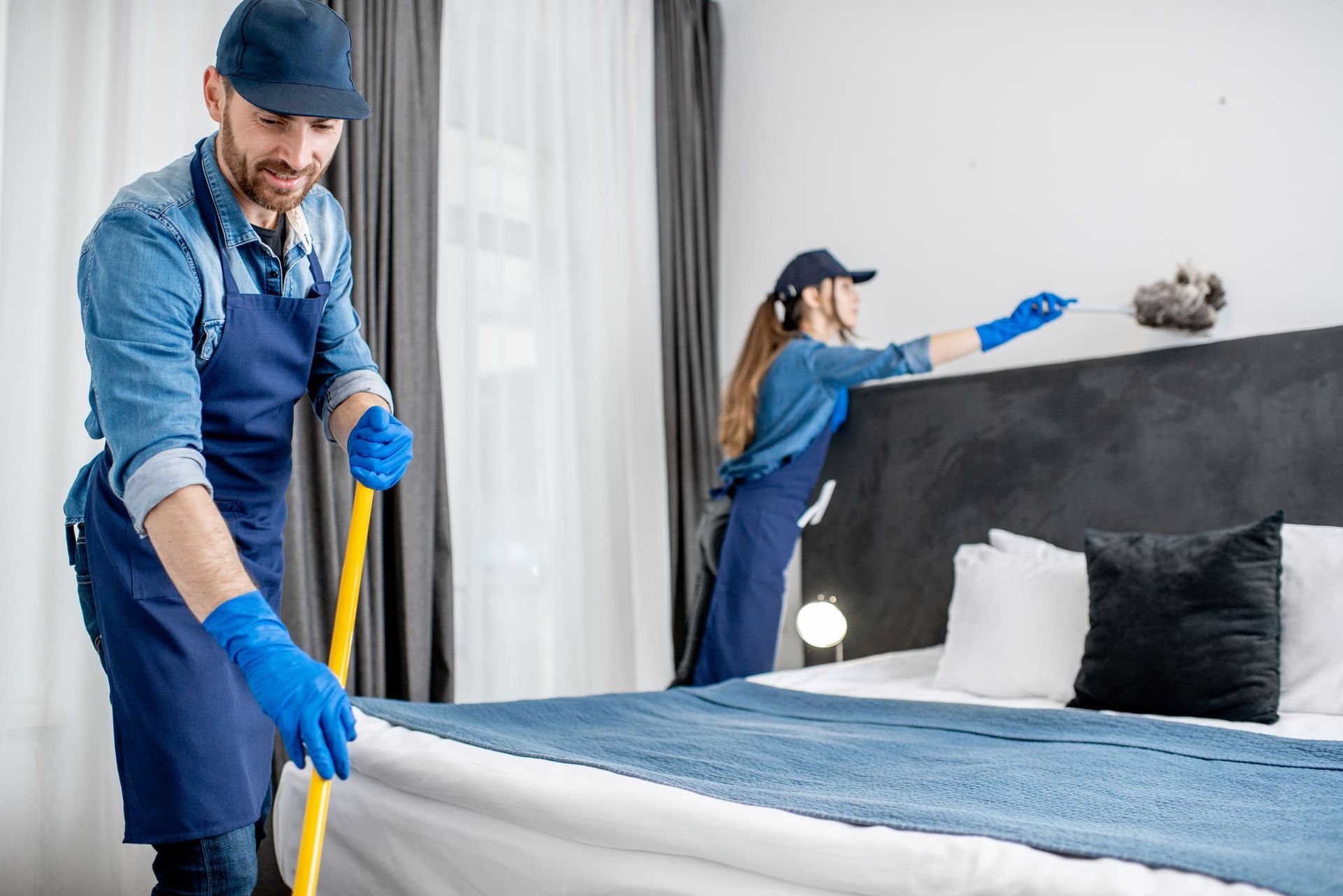 Un hombre y una mujer están limpiando una habitación de hotel.