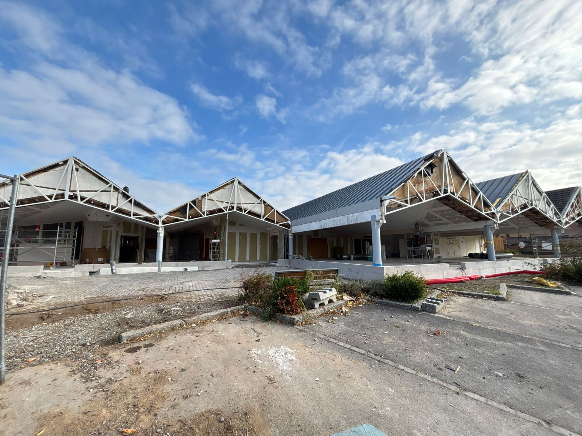 Bâtiment en cours de rénovation, charpente apparente, ciel couvert, vue extérieure.