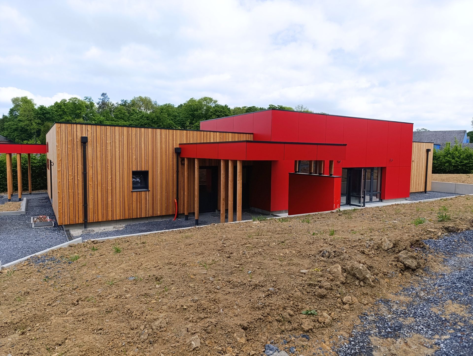 Maison moderne avec revêtement en bois et accents rouges par temps nuageux.