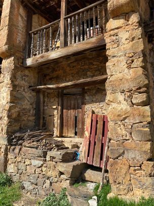 Un edificio de piedra con puerta de madera y balcón.
