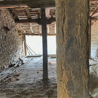 Una habitación con muchas vigas de madera y una pared de piedra.