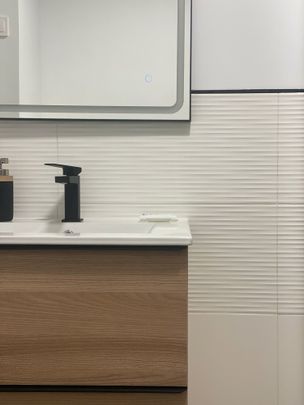 Un baño con lavabo, espejo y dispensador de jabón.