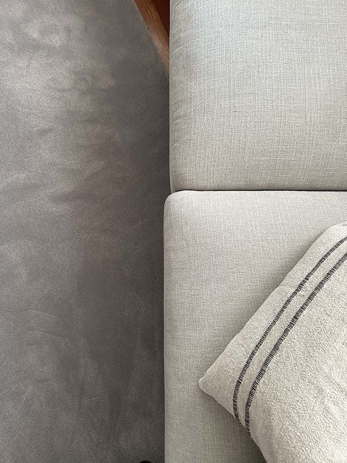 Una vista desde arriba muestra cojines de tela de color beige claro junto a una superficie lisa de color gris oscuro.