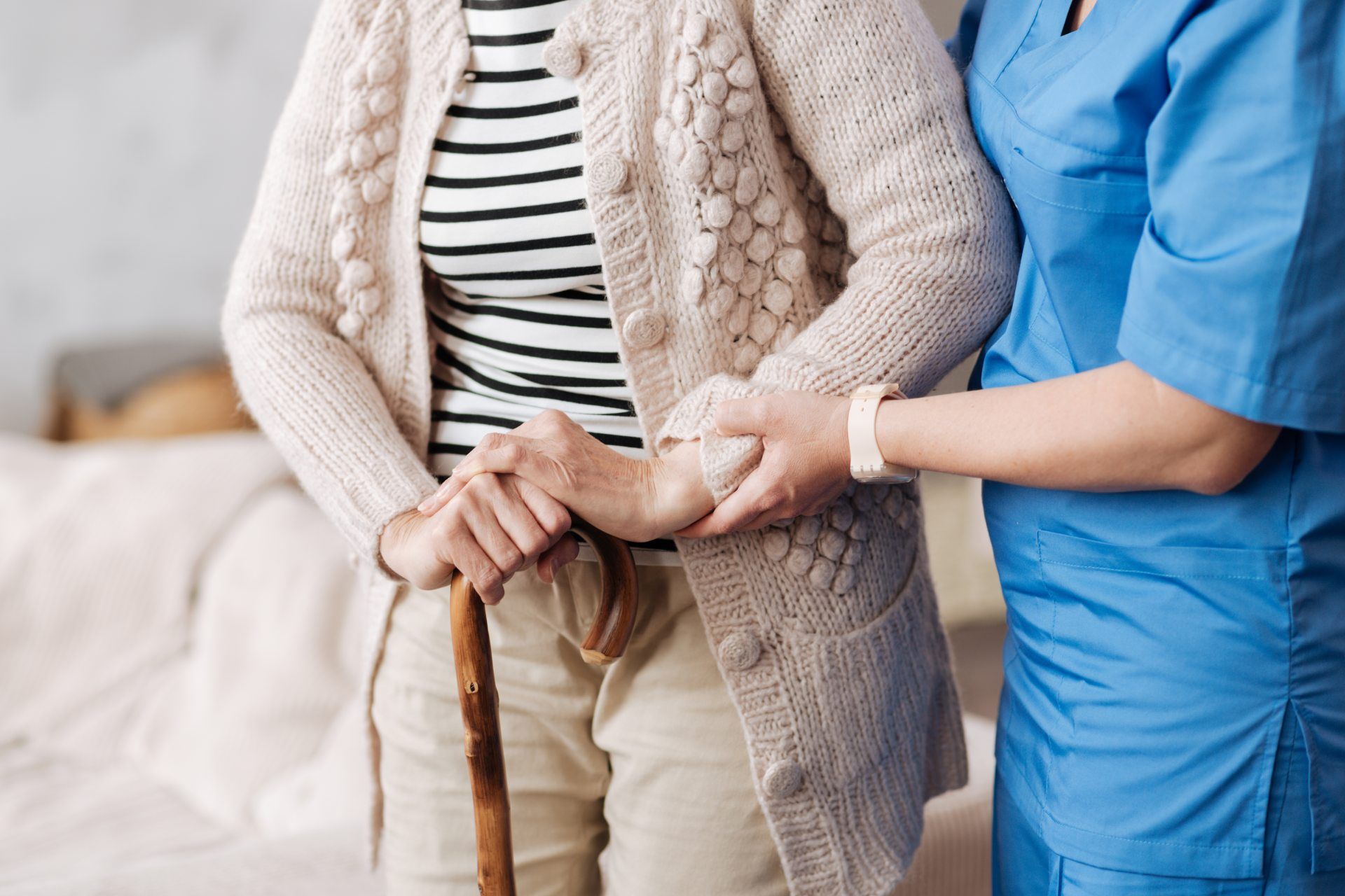 fairpflegt GbR – eine Pflegefachkraft stützt eine Seniorin mit Gehstock