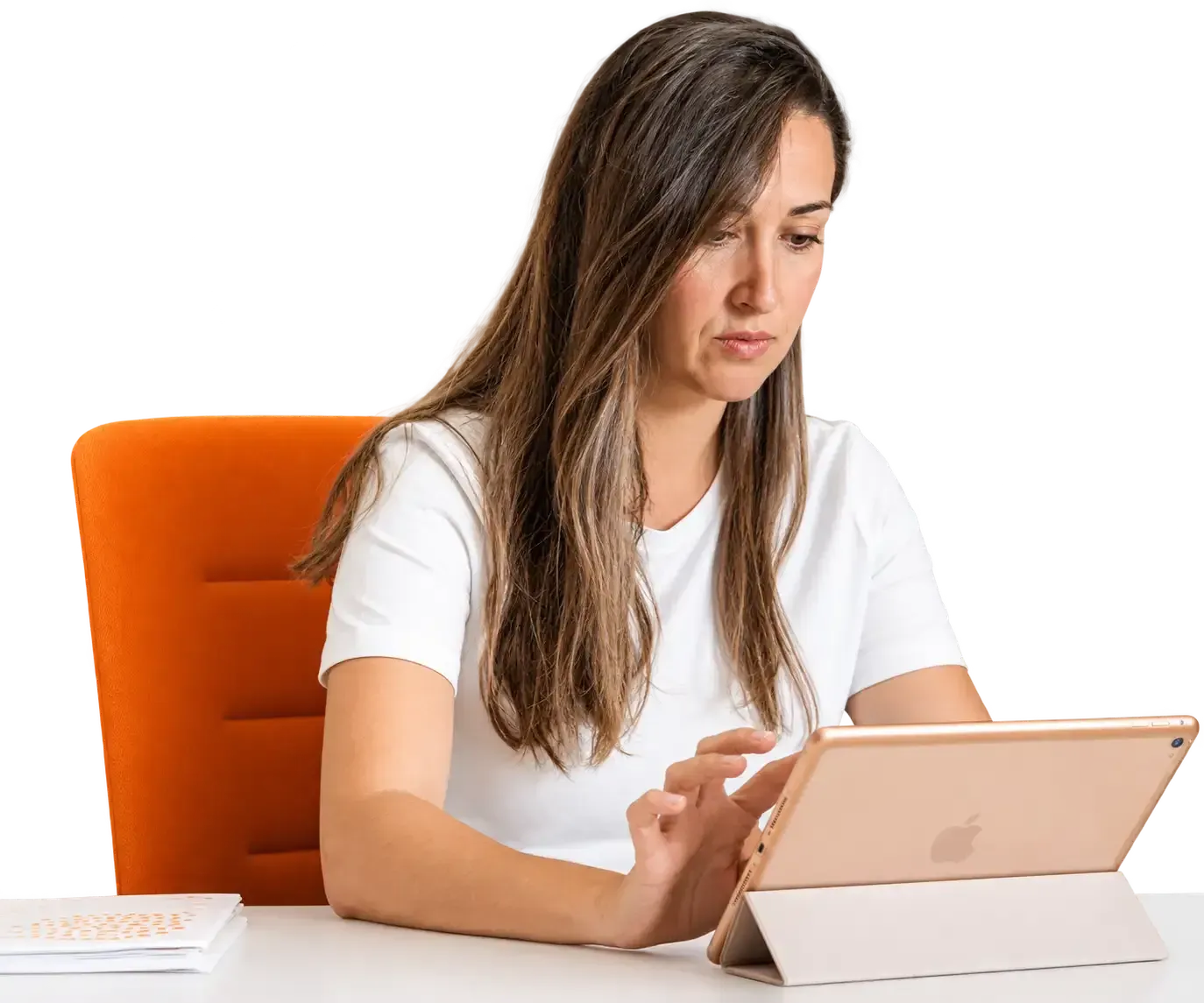 Mujer usando una tableta en un escritorio con una silla naranja.