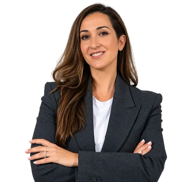 Profesional sonriente con blazer oscuro y brazos cruzados sobre fondo blanco.