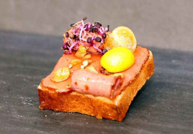 Drei Tassen Cappuccino stehen auf einem Holztisch neben Topfpflanzen.