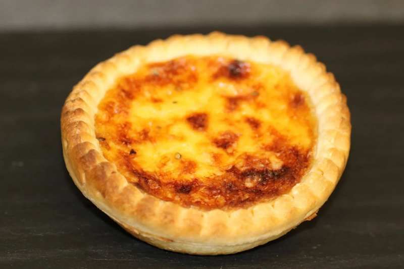 Drei Tassen Cappuccino stehen auf einem Holztisch neben Topfpflanzen.