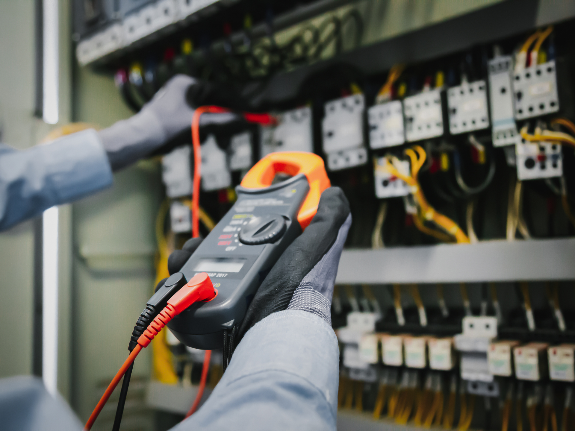 Un électricien utilise un multimètre pour tester les connexions électriques à l'intérieur d'un tableau électrique.