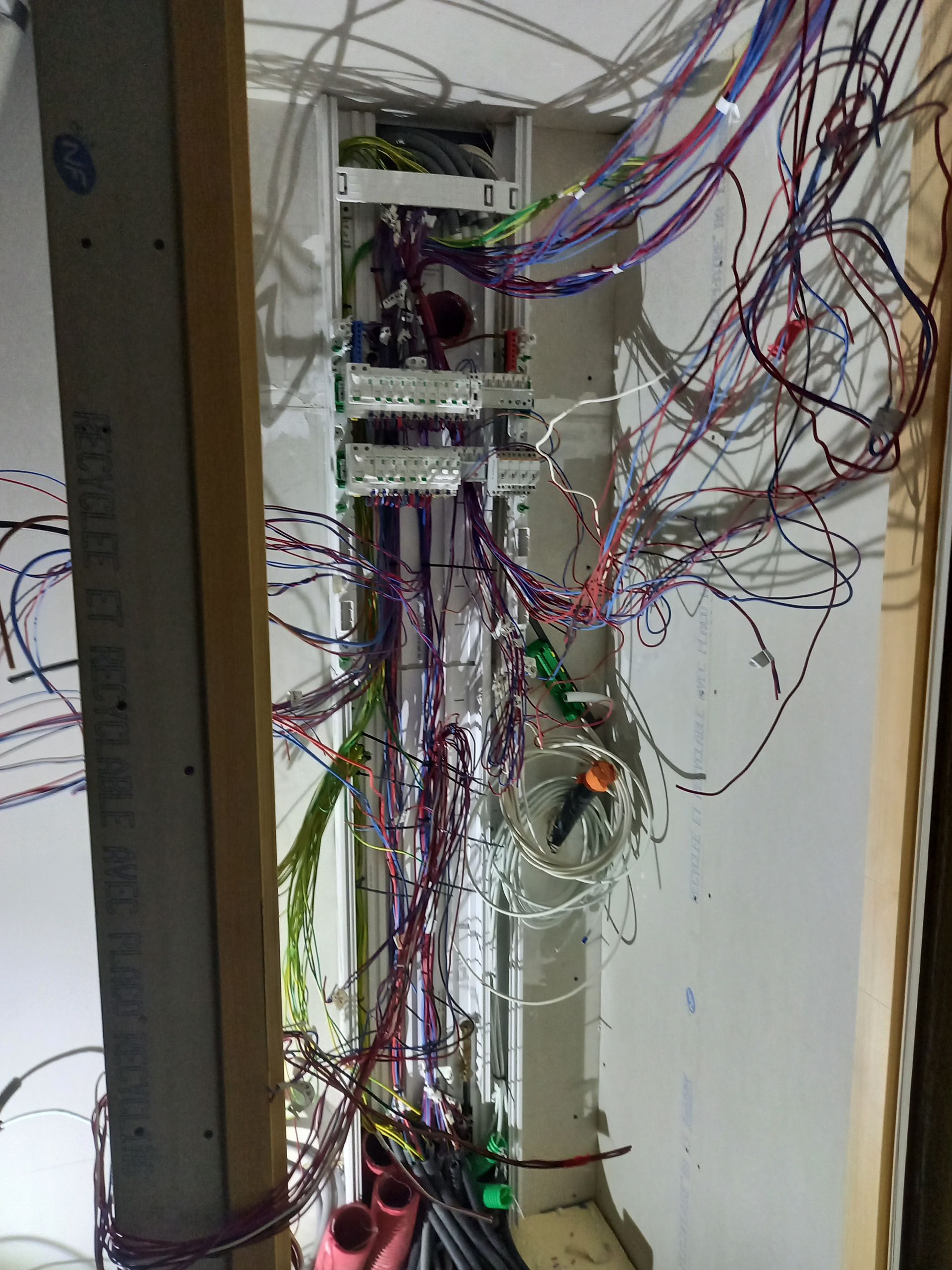 Cavité murale ouverte avec câblage apparent ; nombreux fils de couleur regroupés et disposés verticalement.