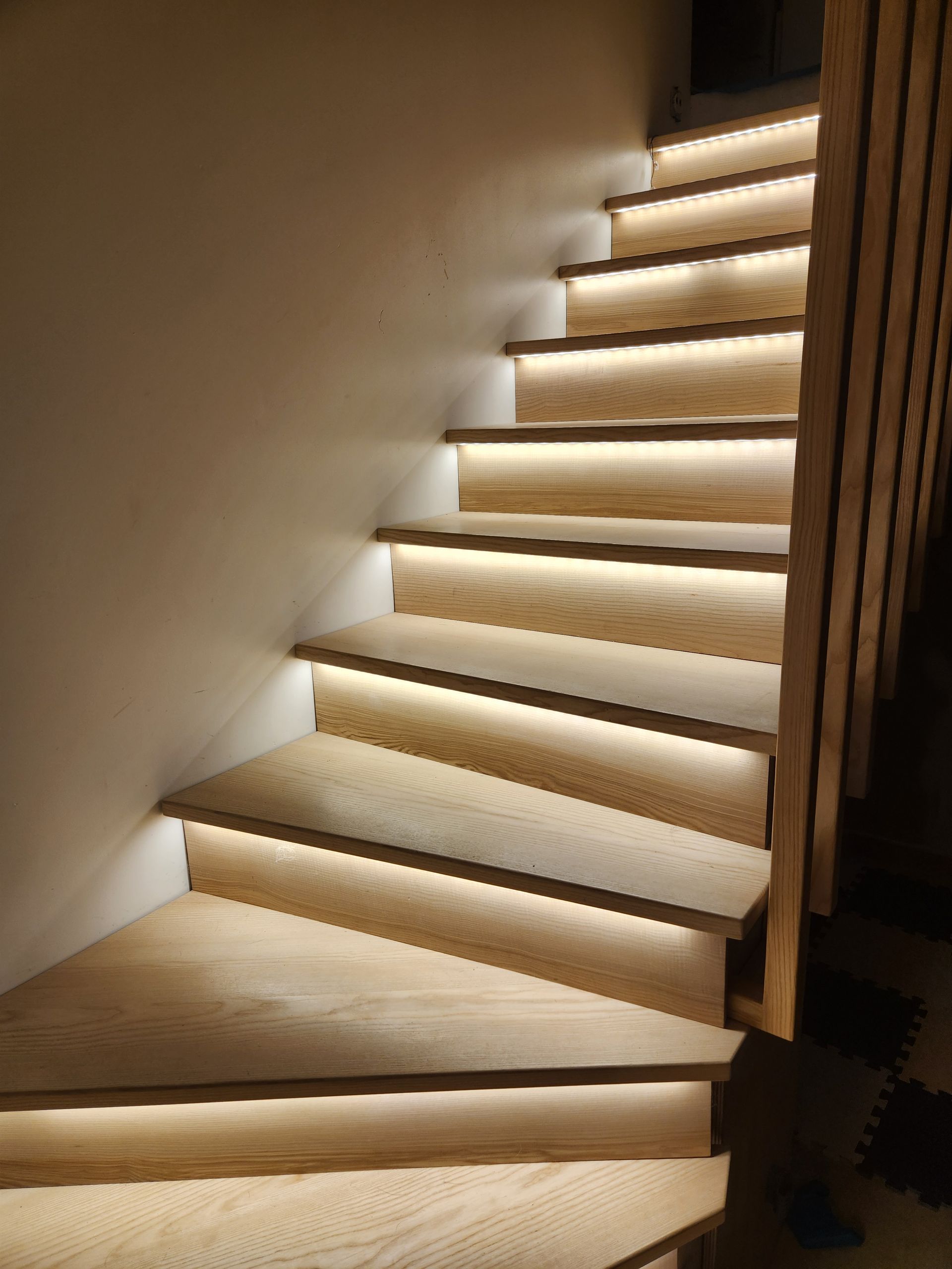 Escalier en bois avec éclairage LED intégré illuminant les marches.