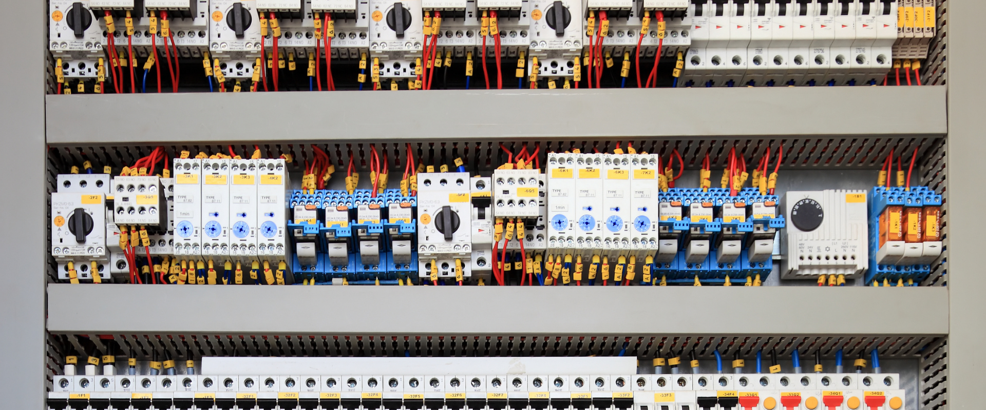 Tableau de commande électrique avec câbles et disjoncteurs.