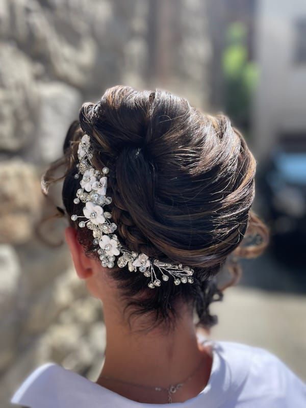 Femme avec une coiffure relevée décorée d'un postiche floral blanc.