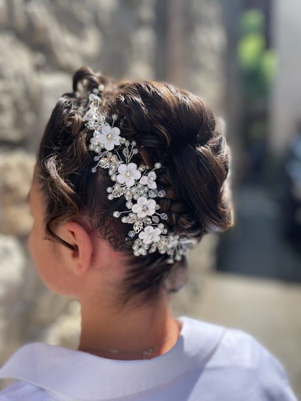 Fille aux cheveux foncés coiffés en chignon, ornés d'accessoires pour cheveux floraux blancs et en cristal, à l'extérieur.