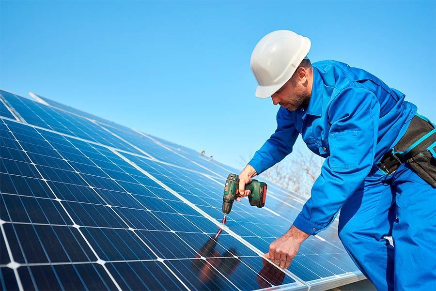 Un hombre está instalando paneles solares en el tejado de un edificio.