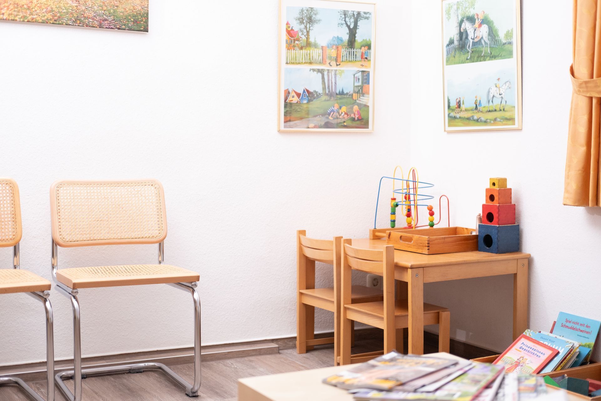 Ein Wartezimmer mit Stühlen, einem Tisch und Spielzeug.