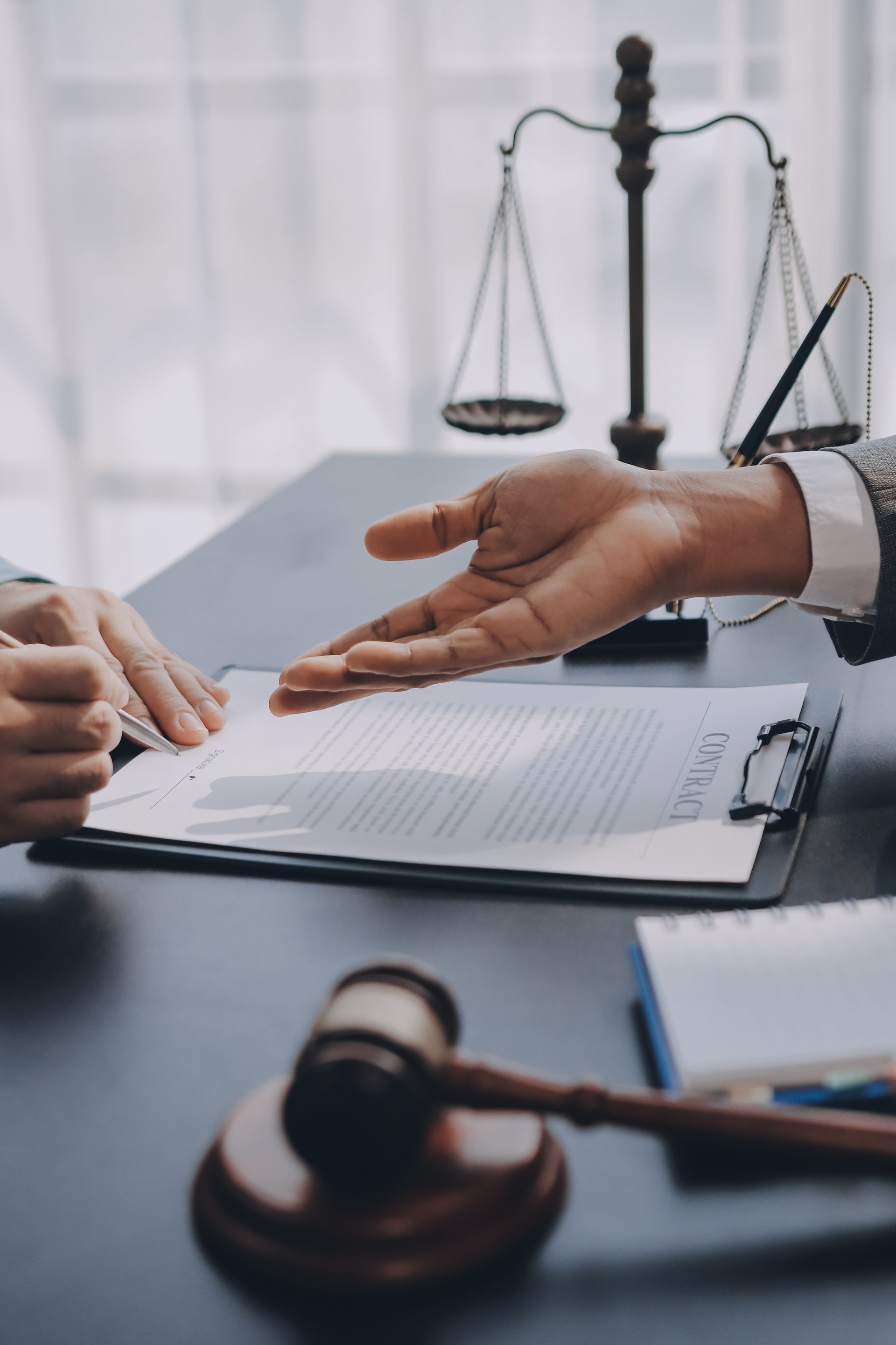 L'avocat désigne des documents du doigt, un marteau et la balance de la justice posés sur le bureau.
