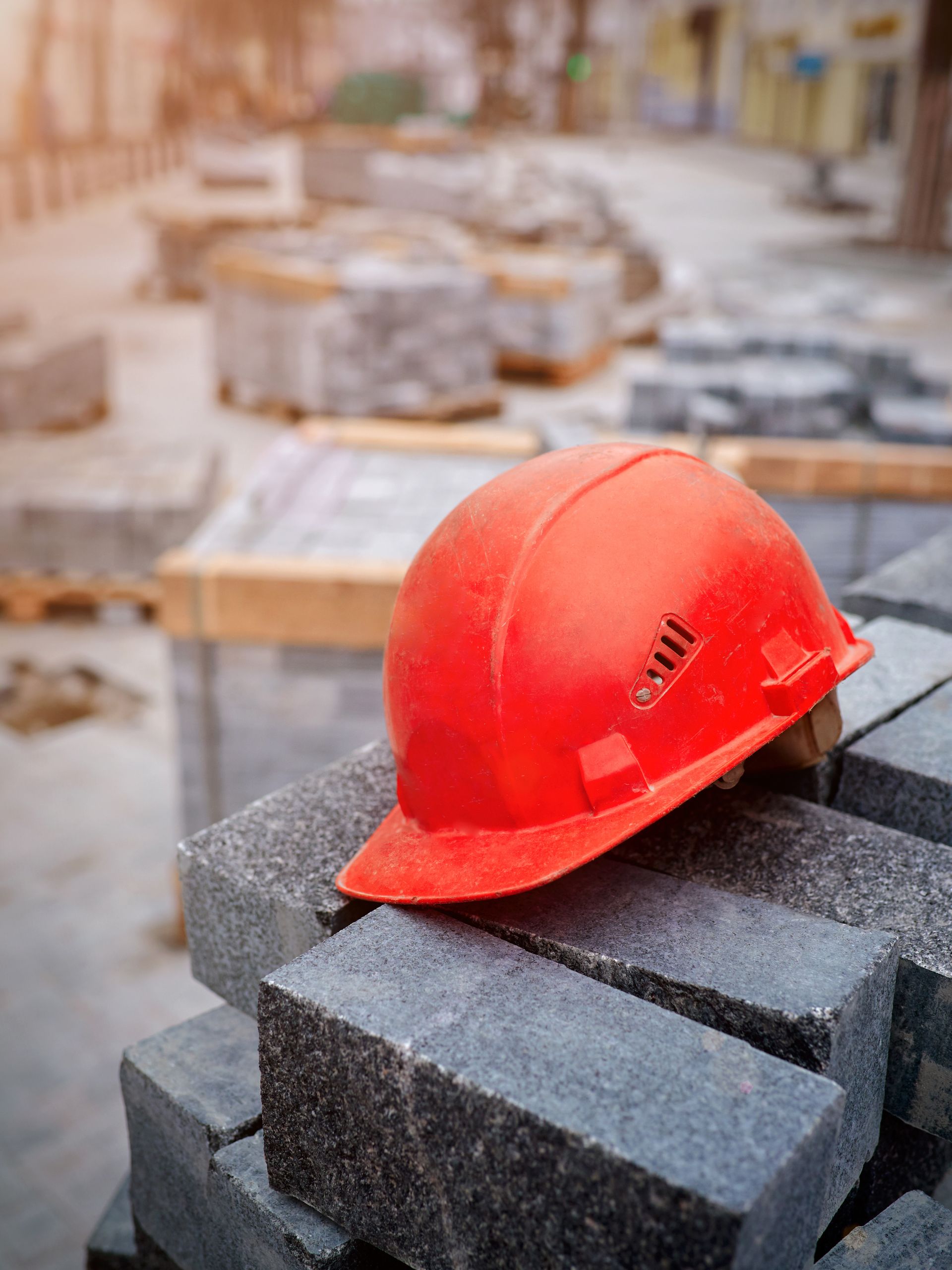 Casque de chantier rouge sur des pavés gris empilés sur un chantier de construction.