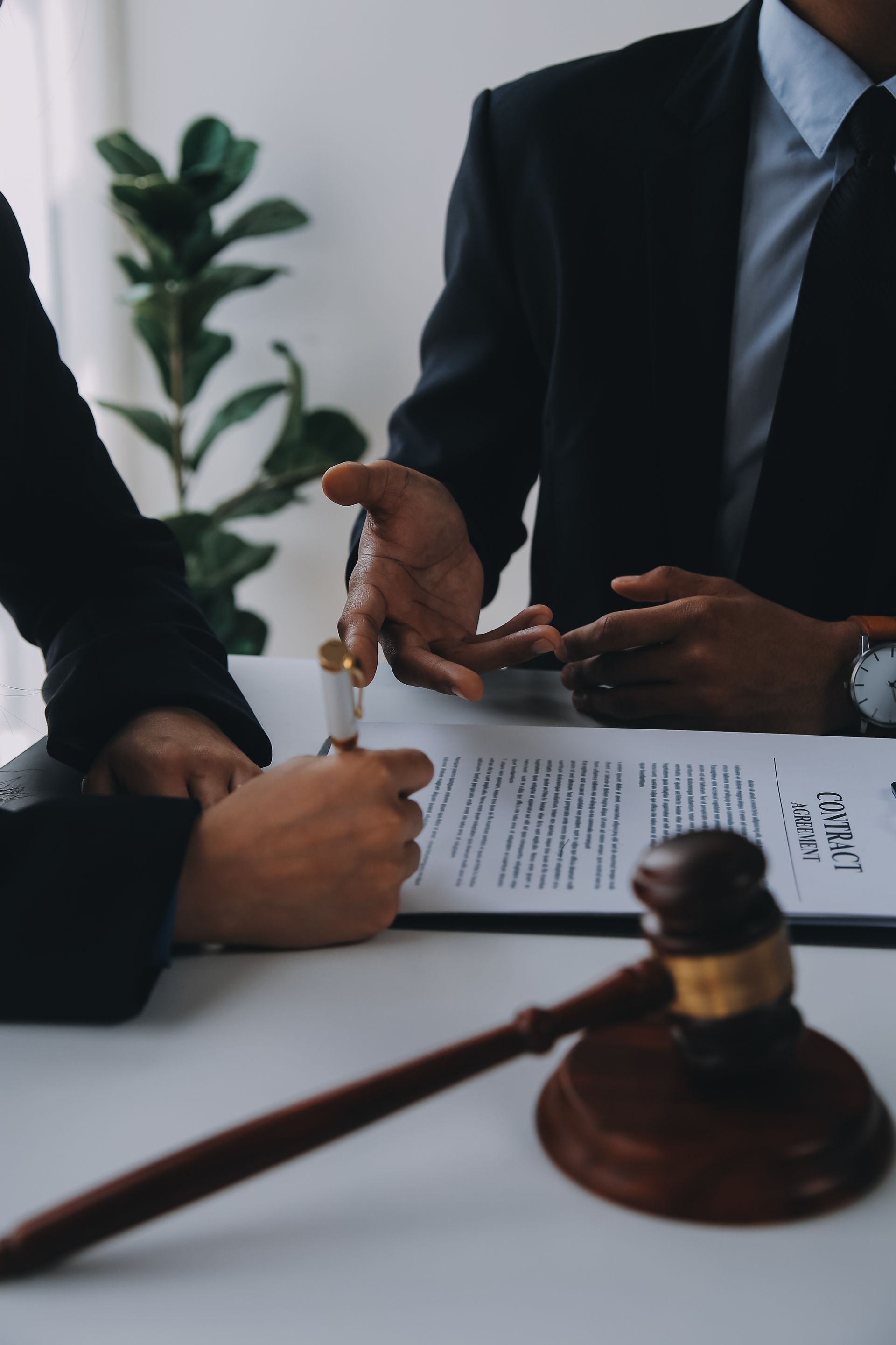 Une poignée de main conclue lors d'un contrat, avec un marteau sur la table dans un cabinet d'avocats.