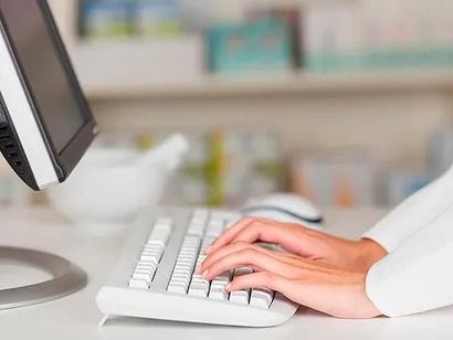 Una persona está escribiendo en un teclado blanco frente a una computadora.