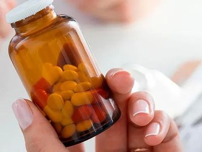 Una persona sostiene un frasco de pastillas en su mano.