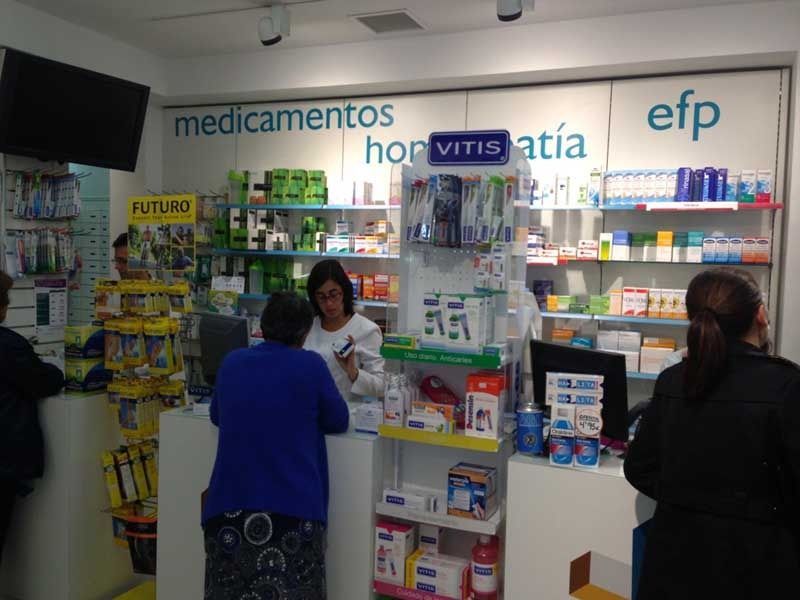 Una mujer con una camisa azul está parada en un mostrador en una farmacia.