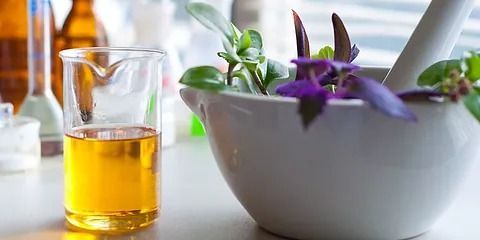 Un mortero con flores y un vaso con líquido.