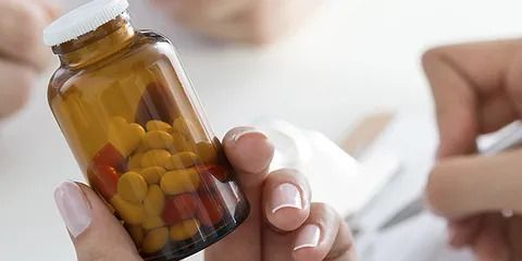 Una persona sostiene un frasco de pastillas y escribe en un trozo de papel.