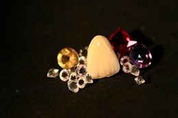 Ein Haufen Diamanten und ein Zahn auf einer schwarzen Oberfläche