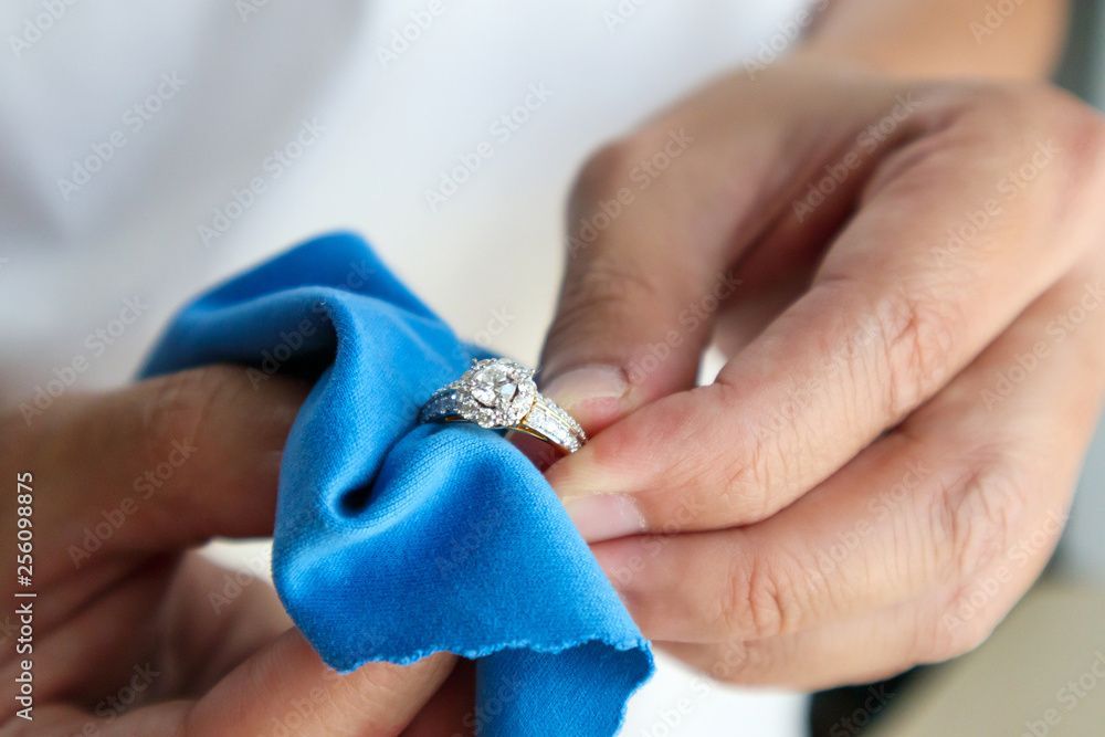 Ring mit Edelsteinen wird mit Mikrofasertuch geputzt
