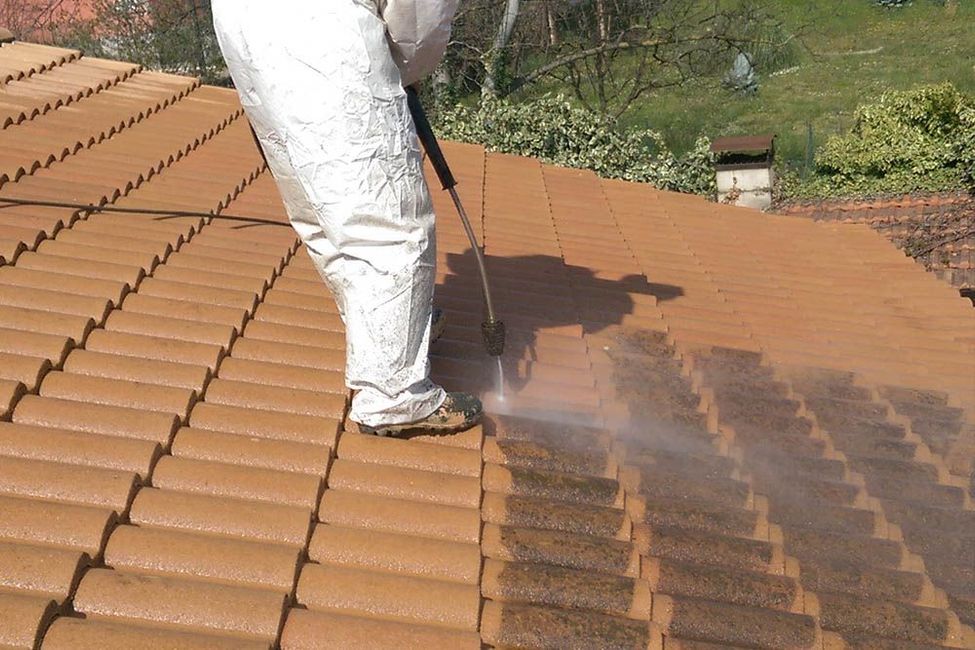 Un couvreur qui nettoie des tuiles