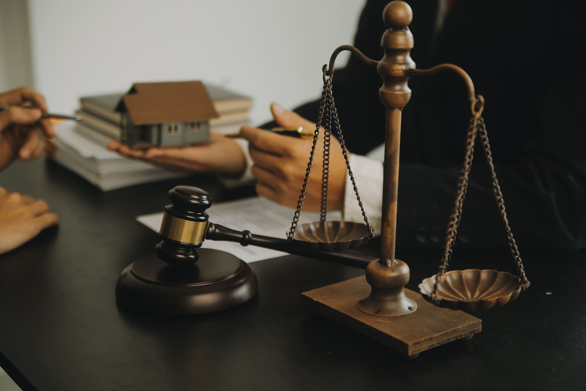 Balanza de la justicia junto a un mazo y una maqueta de casa sobre un escritorio; concepto legal.